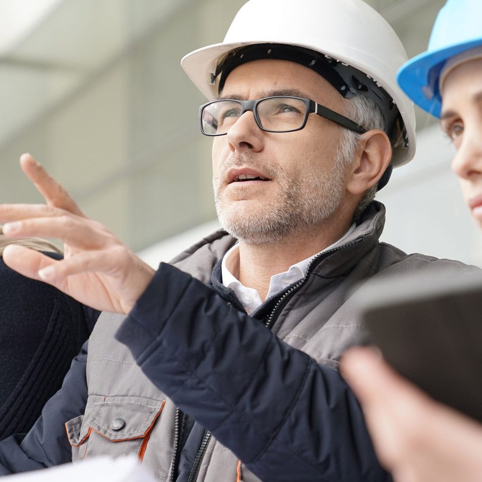 An older architect provides mentorship to a younger architect at a job site.